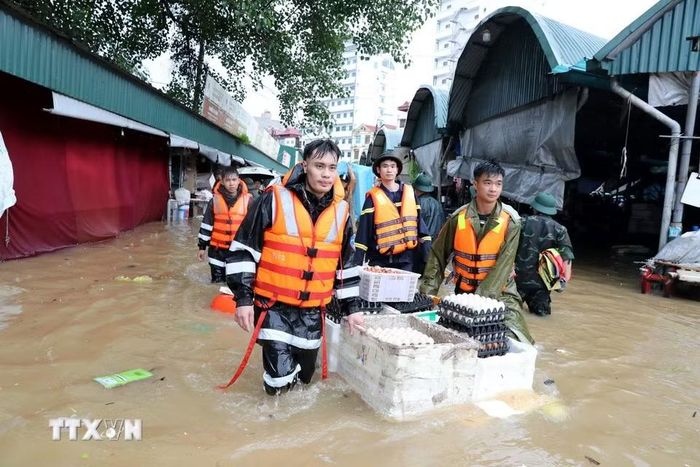 Cán bộ chiến sỹ lực lượng vũ trang tỉnh Lạng Sơn hỗ trợ tiểu thương di chuyển tài sản ra khỏi khu vực ngập sâu. (Ảnh: Văn Đạt/TTXVN)