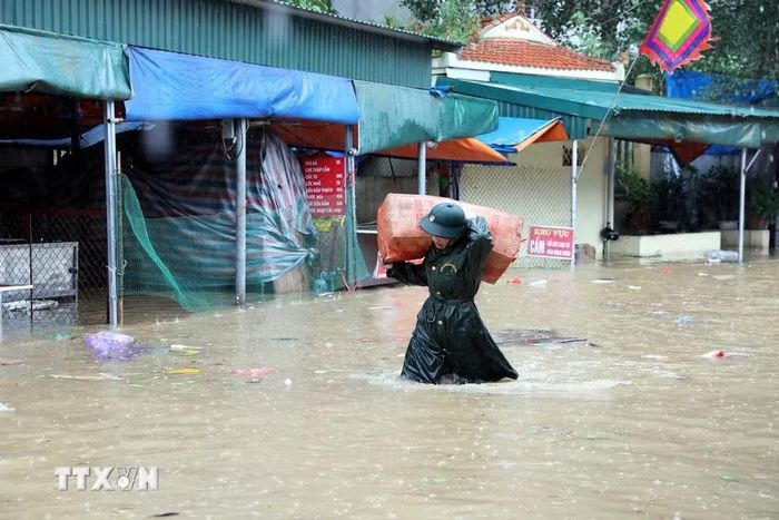 Cán bộ chiến sỹ Bộ Chỉ huy Quân sự tỉnh Lạng Sơn giúp tiểu thương di chuyển tài sản ra khỏi khu vực ngập sâu. (Ảnh: Văn Đạt/TTXVN)