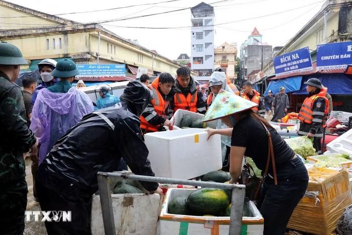 Cán bộ chiến sỹ Bộ Chỉ huy Quân sự tỉnh Lạng Sơn giúp tiểu thương di chuyển tài sản ra khỏi khu vực ngập sâu. (Ảnh: Văn Đạt/TTXVN)