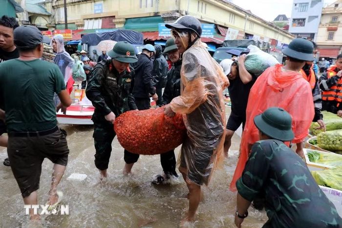 Cán bộ chiến sỹ Bộ Chỉ huy Quân sự tỉnh Lạng Sơn giúp tiểu thương di chuyển tài sản ra khỏi khu vực ngập sâu. (Ảnh: Văn Đạt/TTXVN)
