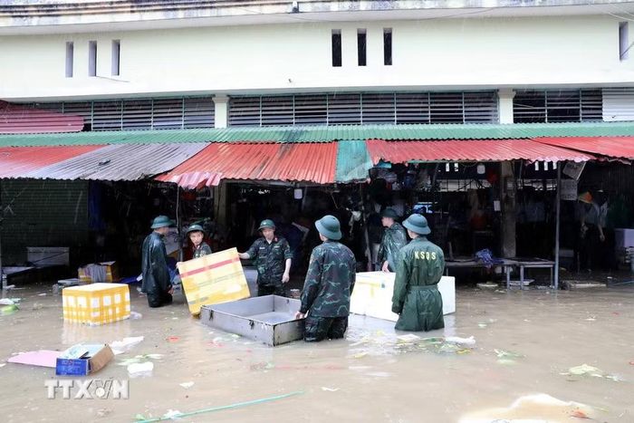 Cán bộ chiến sỹ Bộ Chỉ huy Quân sự tỉnh Lạng Sơn giúp tiểu thương di chuyển tài sản ra khỏi khu vực ngập sâu. (Ảnh: Văn Đạt/TTXVN)