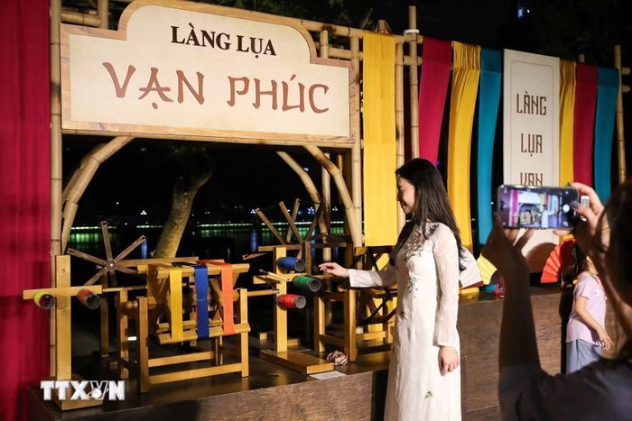 Người dân chụp ảnh lưu lại khoảnh khắc tại gian trưng bày của Làng lụa Vạn Phúc. (Ảnh: Khánh Hòa/TTXVN)