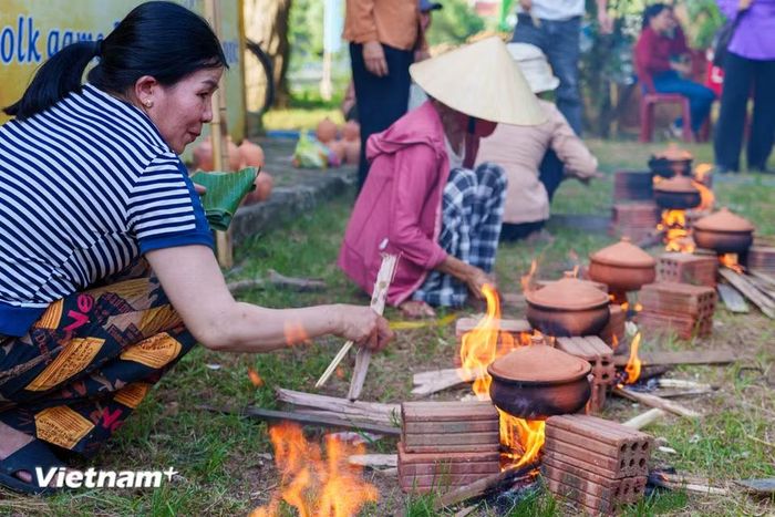 Người tham gia thi tài khéo léo điều chỉnh ngọn lửa củi để đảm bảo nồi cơm đất chín đều và giữ được hương vị. (Ảnh: Thanh Phong/Vietnam+)