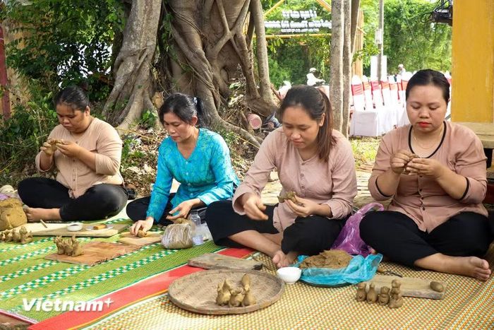 Dưới bóng cây đa cổ thụ, các nữ thợ gốm miệt mài nặn những con tò he đất nhỏ nhắn bằng đôi tay khéo léo. (Ảnh: Thanh Phong/Vietnam+)