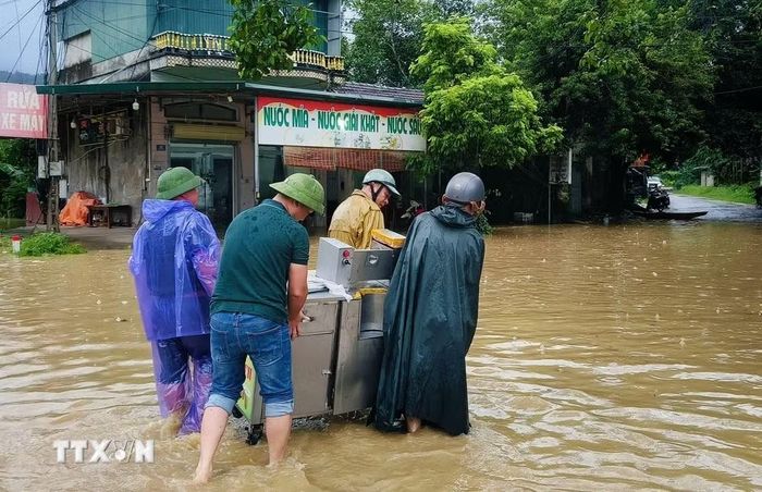 Lực lượng chức năng hỗ trợ người dân di dời tài sản tại xã Sơn Động. (Ảnh: Danh Lam/TTXVN)