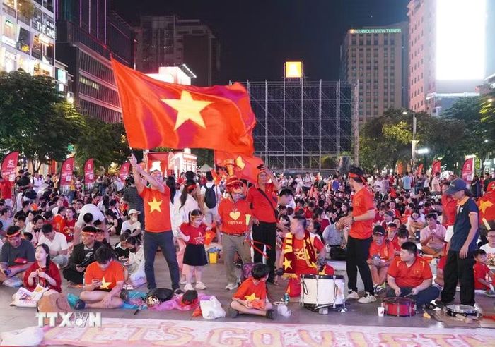 Người hâm mộ với cờ đỏ sao vàng, trống và kèn tập trung tại phố đi bộ Nguyễn Huệ, sẵn sàng tiếp lửa cho đội tuyển Việt Nam trong trận chung kết lượt đi ASEAN Hyundai Cup 2026 gặp Thái Lan. (Ảnh: Trung Tuyến/TTXVN)