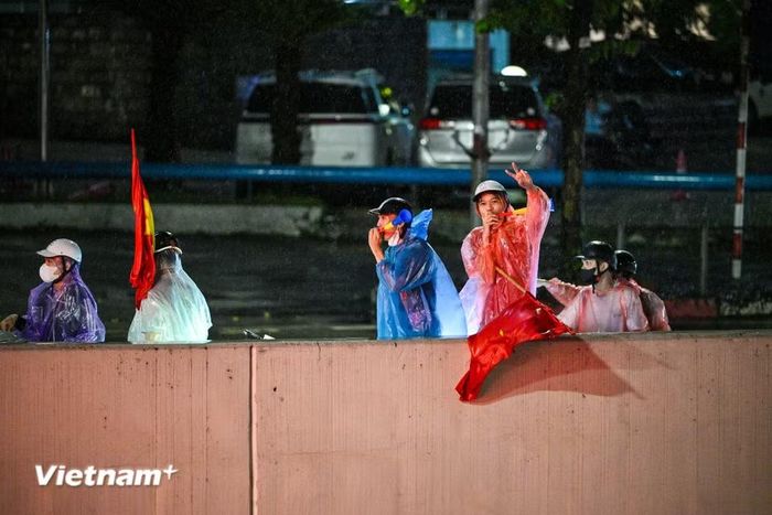 Trên nhiều tuyến phố, những lá cờ đỏ sao vàng tung bay giữa dòng người. Các nhóm cổ động viên liên tục hô vang “Việt Nam vô địch” tạo nên những màn ăn mừng sôi động. (Ảnh: Minh Sơn/Vietnam+)