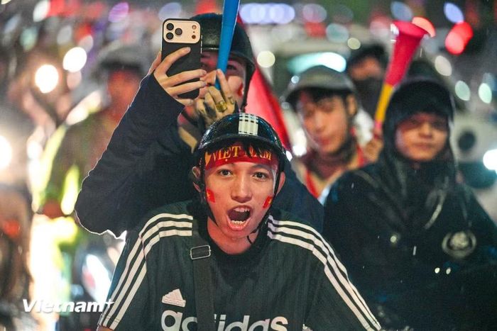 Giữa màn mưa đêm, những lá cờ đỏ sao vàng vẫn nổi bật trên các tuyến phố. Dòng người tiếp tục nối dài, tiếng hô “Việt Nam vô địch” vang lên trong niềm vui chiến thắng, biến nhiều tuyến phố Hà Nội thành một lễ hội bóng đá đầy màu sắc. (Ảnh: Minh Sơn/Vietnam+)