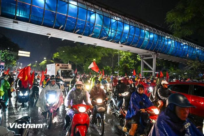Dù trời mưa nặng hạt, những tuyến phố trung tâm Thủ đô vẫn rực sắc đỏ của cờ Tổ quốc, tiếng hò reo “Việt Nam vô địch” vang lên không ngớt. (Ảnh: Minh Sơn/Vietnam+)