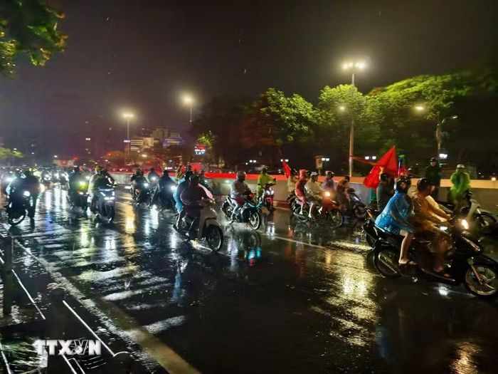 Cơn mưa xuyên suốt cả ngày không ngăn được niềm vui của người hâm mộ Thủ đô. (Ảnh: Minh Quyết/TTXVN)