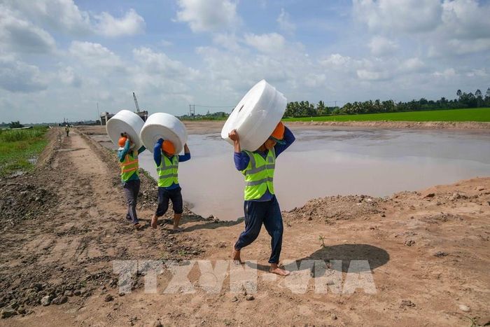 Công nhân tập kết vật liệu đến vị trí thi công gia tải nền đường dự án thành phần 2, cao tốc Châu Đốc - Cần Thơ - Sóc Trăng đoạn qua xã Thạnh Quới, thành phố Cần Thơ. Ảnh: Thanh Liêm - TTXVN