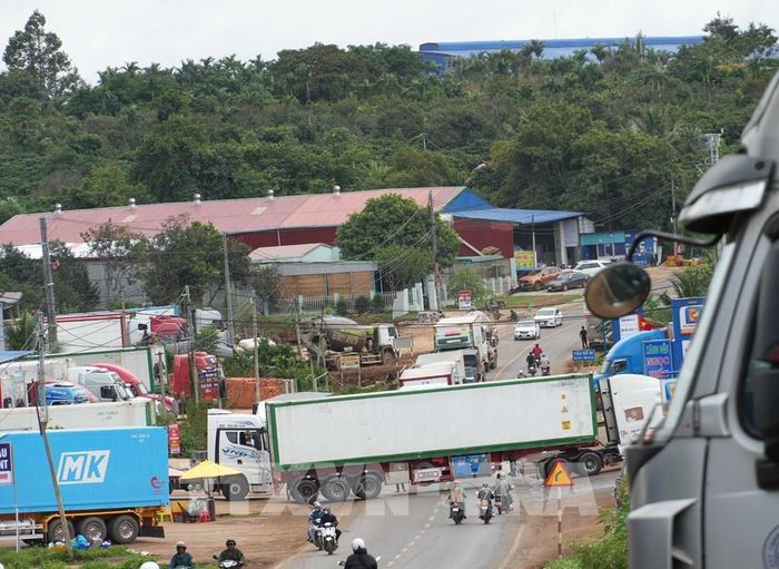 Xe container di chuyển vào bãi tập kết và chắn ngang đường trên quốc lộ 26. Ảnh: Tuấn Anh – TTXVN