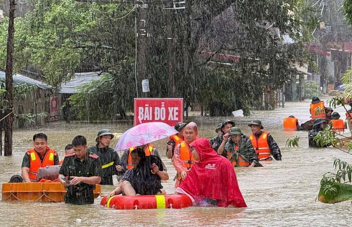 Lực lượng chức năng giúp người dân vượt mưa bão đến vị trí an toàn