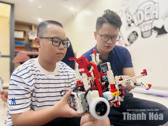 Em Lê Huy Thế Vinh (học sinh lớp 8, Trường Tiểu học, THCS và THPT FPT Thanh Hóa) cùng thầy Lê Minh Đức, Giám đốc Trung tâm Sáng tạo Công nghệ 8-bit trao đổi ý tưởng, hoàn thiện mô hình robotics.
