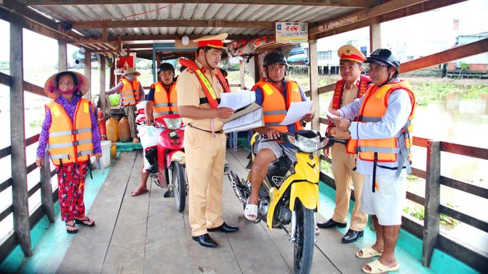 Lực lượng Cảnh sát đường thủy (Phòng CSGT Công an tỉnh Cà Mau) phát tờ rơi tuyên truyền Luật Giao thông đến hành khách đi đò, phà.