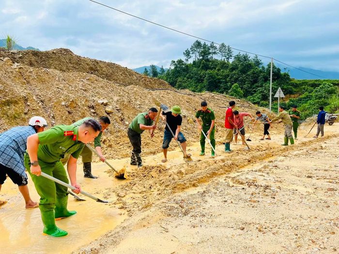 Cán bộ, đoàn viên Công an xã Phình Hồ cùng các lực lượng khắc phục bùn đất trên đường.