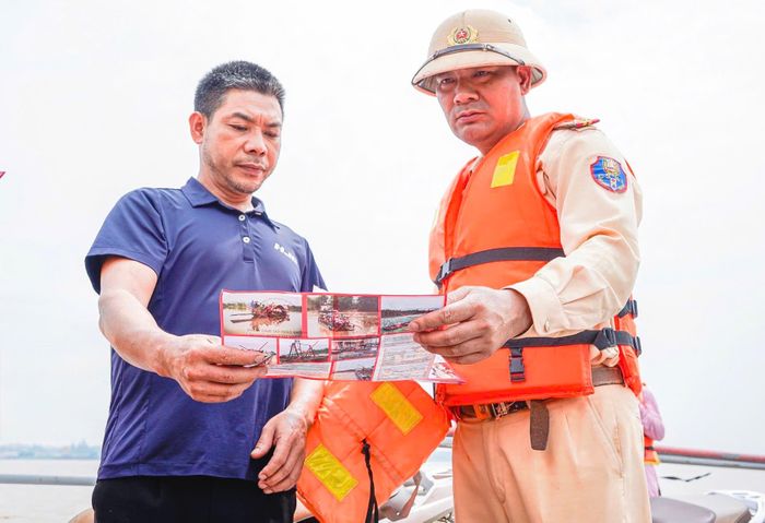 Trung tá Trịnh Văn Trường phát tờ rơi tuyên truyền an toàn giao thông đường thuỷ cho một chủ phương tiện. Ảnh: Đức Tuấn