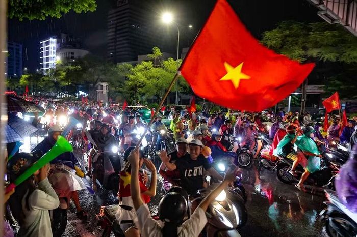 Nụ cười rạng rỡ và cái vẫy tay chào thân thiện hướng về ống kính máy ảnh giữa dòng xe cộ ken đặc.