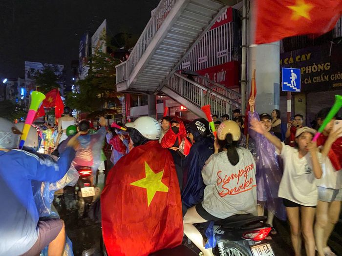 Các cổ động viên mang theo cờ đỏ, kèn thổi cùng nhau ăn mừng bất chấp mưa gió
