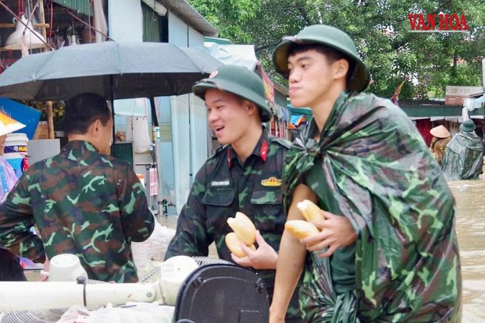 Bộ đội lội giữa dòng nước ngập, trên tay vẫn cầm bánh mì, tranh thủ ăn vội trong lúc làm nhiệm vụ hỗ trợ người dân Lạng Sơn
