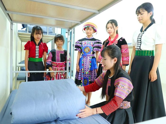 Giáo viên hướng dẫn học sinh gấp chăn, màn ngay ngắn, rèn luyện tính tự giác và ngăn nắp trong sinh hoạt nội trú