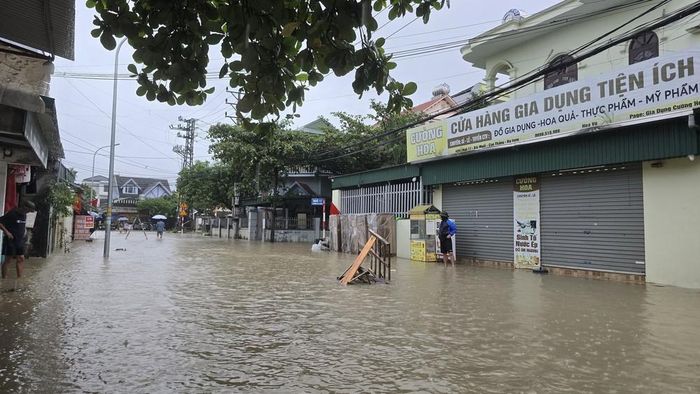 Nước ngập cao lên cao, người dân phải mang các vật dụng để trước nhà chặn xe ô tô đi qua gây tràn nước vào nhà. Ảnh: Thanh Vân - TTXVN