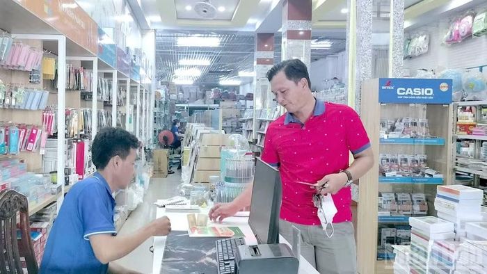 Phụ huynh tìm mua các đầu sách giáo khoa còn thiếu cho con tại quầy thanh toán của một cửa hàng sách-thiết bị giáo dục vùng nội ô Cà Mau trước thềm năm học mới. (Ảnh: HỮU TÙNG)