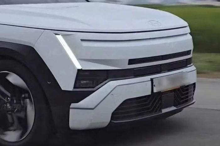 Phần đầu xe Hyundai Tucson 2027 gây chú ý với dải đèn LED chạy ngang kết hợp cụm đèn định vị hình chữ H đặt ở hai bên. Cụm đèn chính được hạ thấp, nằm tách biệt phía dưới, trong khi phần đầu xe dựng đứng hơn trước. Lưới tản nhiệt cũng được thiết kế lại theo hướng kín và gọn hơn.