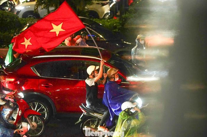 Tại nhiều tuyến phố trung tâm, người hâm mộ nhanh chóng đổ ra đường. Giữa màn mưa trắng xóa, những lá cờ đỏ sao vàng vẫn tung bay, tiếng hô “Việt Nam”, “Việt Nam vô địch” vang lên không ngớt.