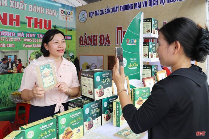  Nếu trước đây hội chợ chủ yếu là nơi trưng bày và bán sản phẩm trực tiếp thì nay cách tiếp cận thị trường đã thay đổi. Nhiều chủ cơ sở kết hợp bán hàng trực tiếp với livestream, giới thiệu sản phẩm trên nền tảng số, biến không gian hội chợ thành điểm kết nối giữa thị trường truyền thống và thị trường trực tuyến. Trong ảnh: Chủ cơ sở sản xuất bánh ram Anh Thu (phường Hà Huy Tập) livestream bán hàng tại hội chợ. 