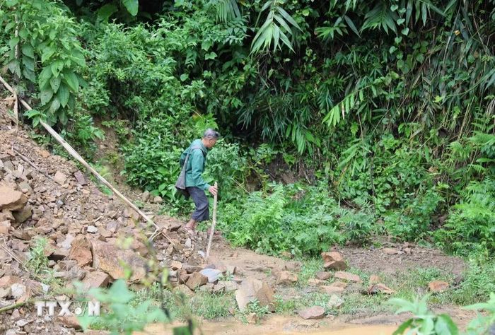 Người dân bản Xốp Kho (xã Nga My, Nghệ An) khó khăn khi tìm cách di chuyển qua điểm sạt lở trên tuyến đường Xốp Kho- Na Ngân. (Ảnh: Xuân Tiến/TTXVN)