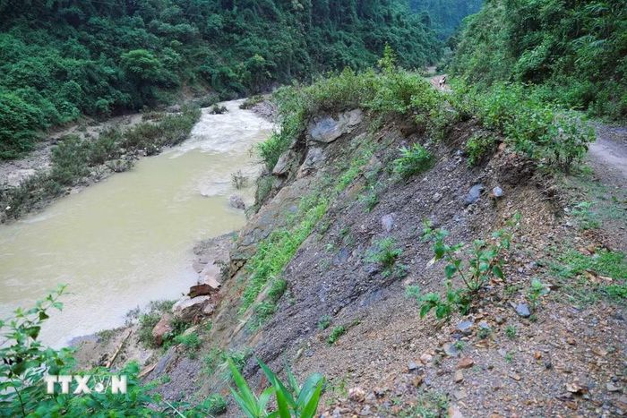 Mưa lớn khiến taluy trên tuyến đường độc đạo vào bản Na Ngân (xã Nga My, Nghệ An) bị sạt trượt, đất đá tràn xuống sát mép suối, tiềm ẩn nguy cơ tiếp tục sạt lở và gây chia cắt giao thông. (Ảnh: Xuân Tiến/TTXVN)