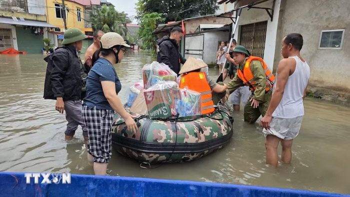 Lực lượng chức năng hỗ trợ người dân phường Tam Thanh, tỉnh Lạng Sơn vận chuyển nhu yếu phẩm vào vùng ngập lụt.(Ảnh: Quang Duy/TTXVN)