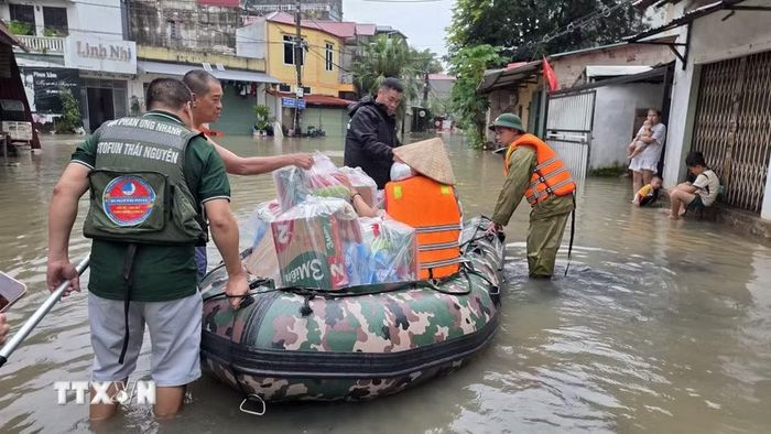 Lực lượng chức năng hỗ trợ người dân phường Tam Thanh, tỉnh Lạng Sơn vận chuyển nhu yếu phẩm vào vùng ngập lụt.(Ảnh: Quang Duy/TTXVN)