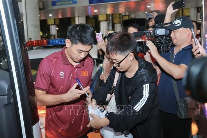 Đình Bắc ký tặng người hâm mộ tại sân bay quốc tế Nội Bài. Ảnh: Minh Quyết/TTXVN
