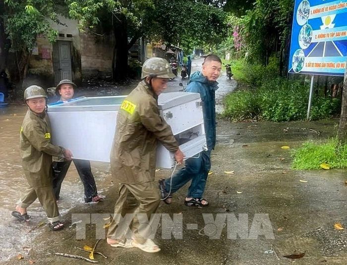 Lực lượng chức năng hỗ trợ người dân di dời tài sản tại xã Sơn Động. Ảnh: Danh Lam - TTXVN 