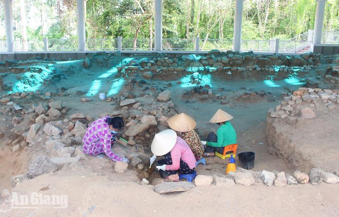 Công nhân cẩn trọng làm sạch tầng văn hóa khảo cổ dưới mái che di tích dưới sự hướng dẫn của các chuyên gia.