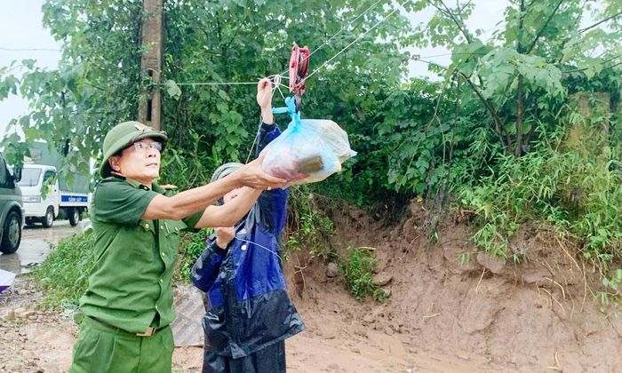 Công an xã Đại Sơn phối hợp với lực lượng xung kích phòng, chống thiên tai địa phương vận chuyển nhu yếu phẩm bằng ròng rọc.