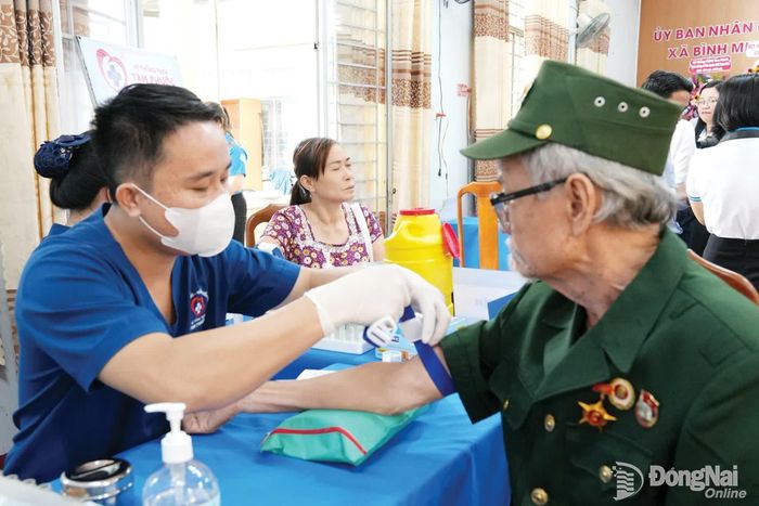 Một cựu chiến binh ở xã Bình Minh được nhân viên y tế lấy máu làm xét nghiệm khám sàng lọc sức khỏe. Ảnh: Bảo Hân