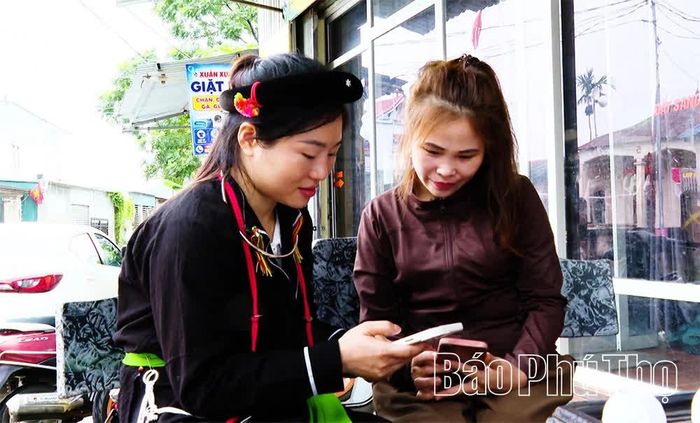 Đảng viên trẻ Tô Thị Thu Lan (bên trái) hướng dẫn người dân cài đặt, sử dụng các ứng dụng số trên điện thoại thông minh.