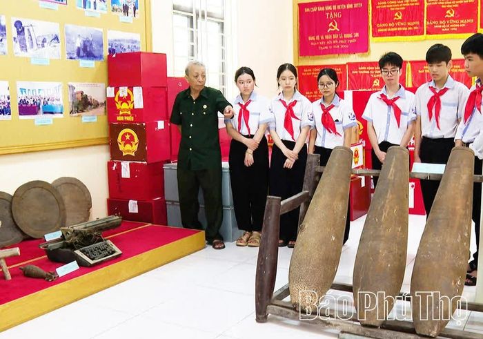 Cựu chiến binh Nguyễn Văn Toán giới thiệu với học sinh những tư liệu, hiện vật về truyền thống cách mạng của quê hương tại Khu lưu niệm Chi bộ Đồn điền Tam Lộng.