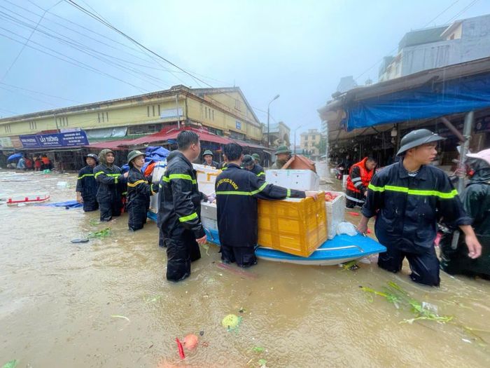 Cán bộ, chiến sĩ hỗ trợ các hộ kinh doanh tại chợ Giếng Vuông di chuyển hàng hóa, tài sản đến nơi an toàn.