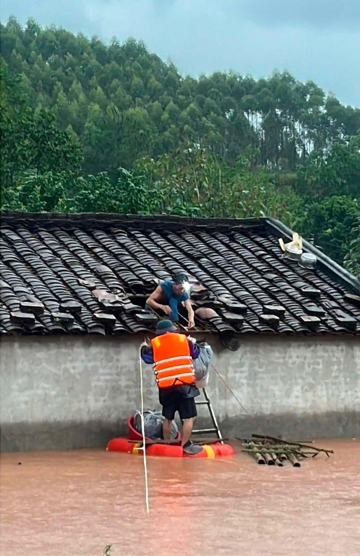 Giữa biển nước mênh mông, người dân phải chui lên mái nhà nhận nhu yếu phẩm.