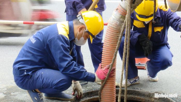 Tại khu vực Xuân Tảo, công nhân kiểm tra, khơi thông hệ thống cống ngầm, sẵn sàng xử lý khi lượng nước trên mặt đường tăng nhanh.
