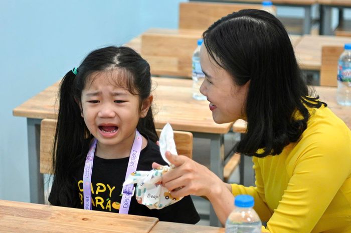  Tại lớp 1A2, cô Trần Hải Hà nhẹ nhàng đón từng học sinh và tìm cách làm quen với các em ngay từ những phút đầu tiên. Được điều chuyển về trường Lê Thị Riêng, cũng là lần đầu phụ trách chủ nhiệm một lớp 1, nhưng cô nhanh chóng bắt nhịp bằng những câu hỏi gần gũi về bản thân các em. Khi có học sinh bật khóc vì chưa quen lớp, cô giáo nhanh chóng mời phụ huynh ra ngoài rồi ở lại trò chuyện, dỗ dành để các em bình tĩnh và làm quen với lớp học mới. 