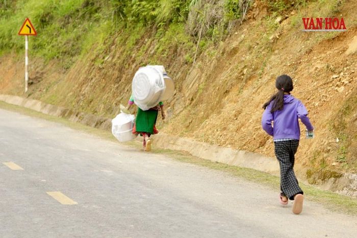 Sau phiên chợ, bà Chúa xách, gùi theo đồ mới mua cùng cháu nhỏ rảo bước trên con đường dốc về bản xa