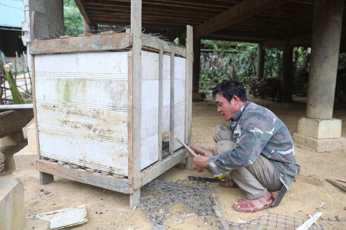 Đường bị chia cắt không thể đi nương rẫy nên đàn ông trong bản Na Ngân (xã Nga My, Nghệ An) tranh thủ làm những công việc nhà, sửa chữa chuồng trại chăn nuôi cho gia đình. Ảnh: Xuân Tiến - TTXVN