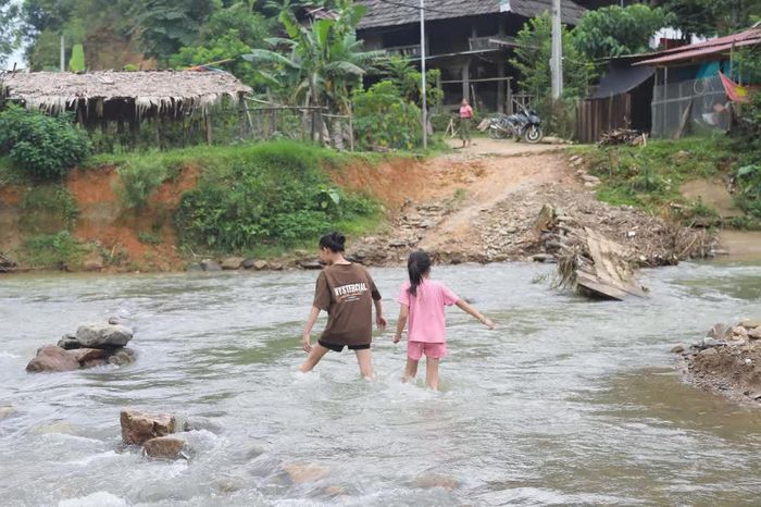Không còn cầu tạm nối giữa 2 cụm dân cư của bản, trẻ em trong bản Na Ngân (xã Nga My, Nghệ An) vất vả khi lội qua suối Nậm Ngân để trở về nhà. Ảnh: Xuân Tiến - TTXVN