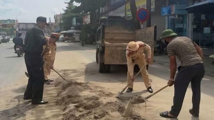 Cảnh sát giao thông và người dân thu dọn cát rơi vãi trên tỉnh lộ 315. (Ảnh: Công an Phú Thọ)