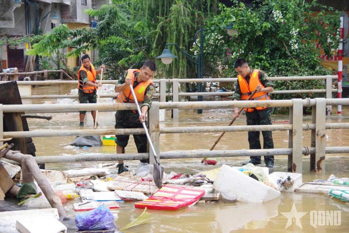 Các chiến sĩ dọn dẹp bùn rác, giúp khơi thông dòng chảy tại điểm ngập úng trên địa bàn phường Tam Thanh. 